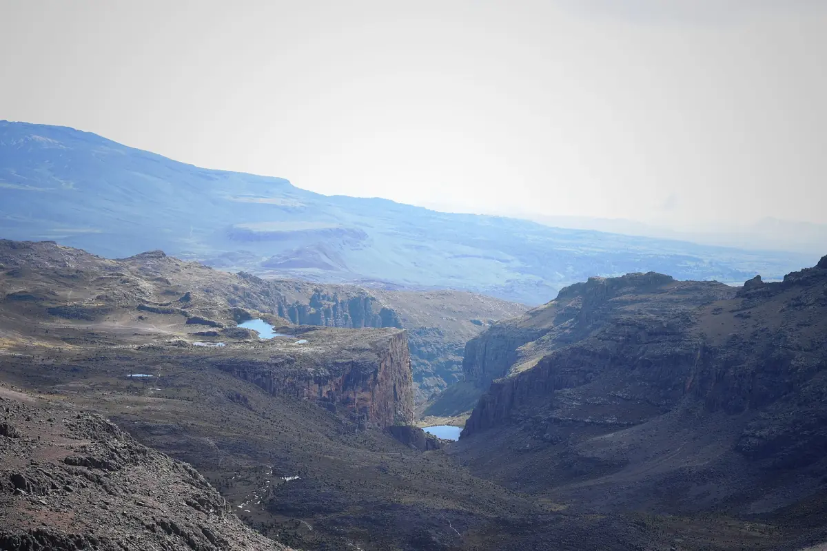 Un lac au loin dans la vallée et des falaises, vus depuis la crête près de Point Lenana