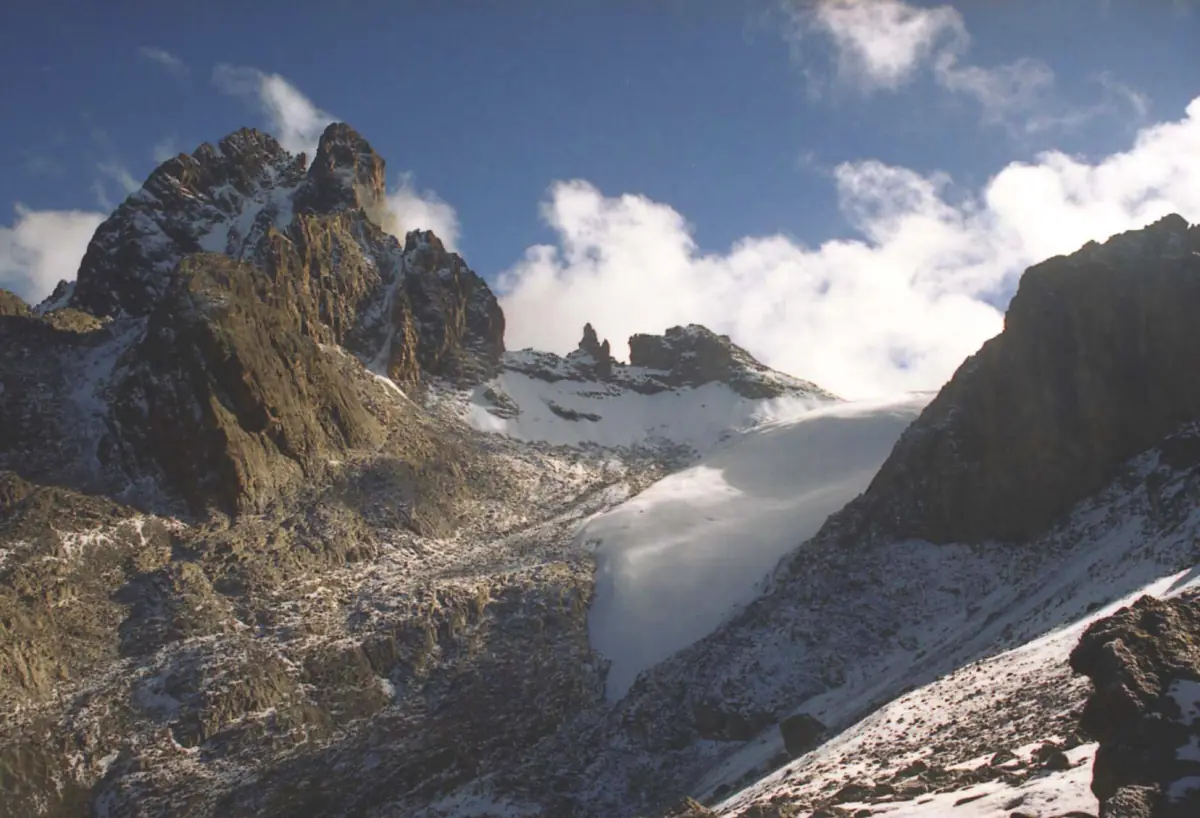 Une langue glaciaire et des sommets enveloppés de nuages dans le cirque de haute montagne