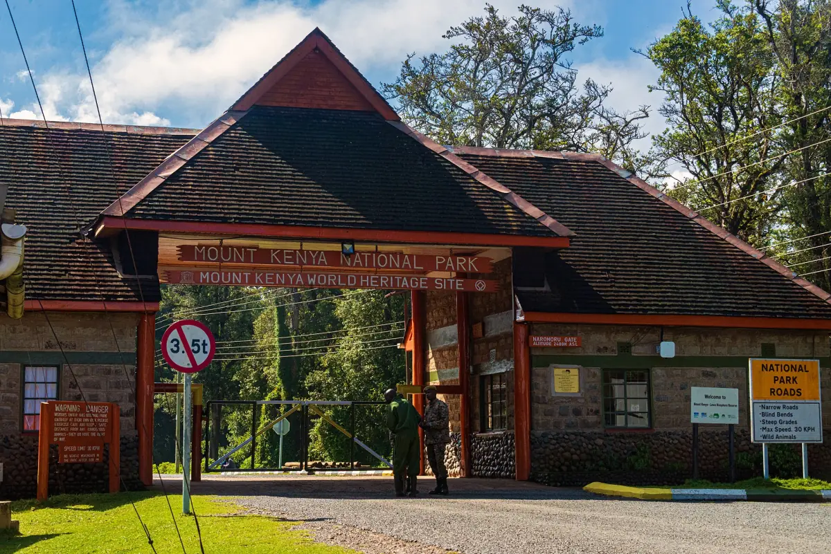 Park gate building with a pitched roof and signs at the forest edge